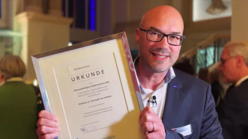 Ein Mann hält eine Urkunde in die Kamera.